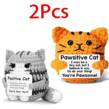 Two handmade crochet cat figurines, one gray and one orange, with positive affirmations written on them.