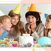 A group of children are shown with a white cake decorated with small animal plush toys and keychain loops.
