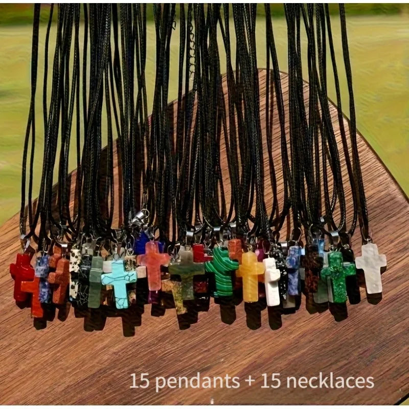 A display of 15 stone cross pendants and 15 necklaces hanging from black cords on a wooden surface.