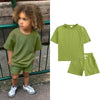 A child models a lime green short sleeve top and matching shorts set.