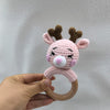 A handmade pink otter rattle and teether ring with brown antlers is held in a hand.