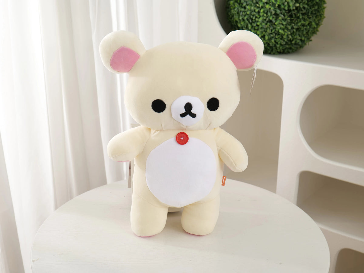 A soft, cream-colored Rilakkuma anime plush bear with pink accents sitting on a white surface.