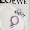 A set of five purple gemstone jewelry pieces including earrings and a bracelet displayed on a white surface.