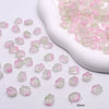 Small pink and green gradient glass beads displayed in a white ceramic mold.