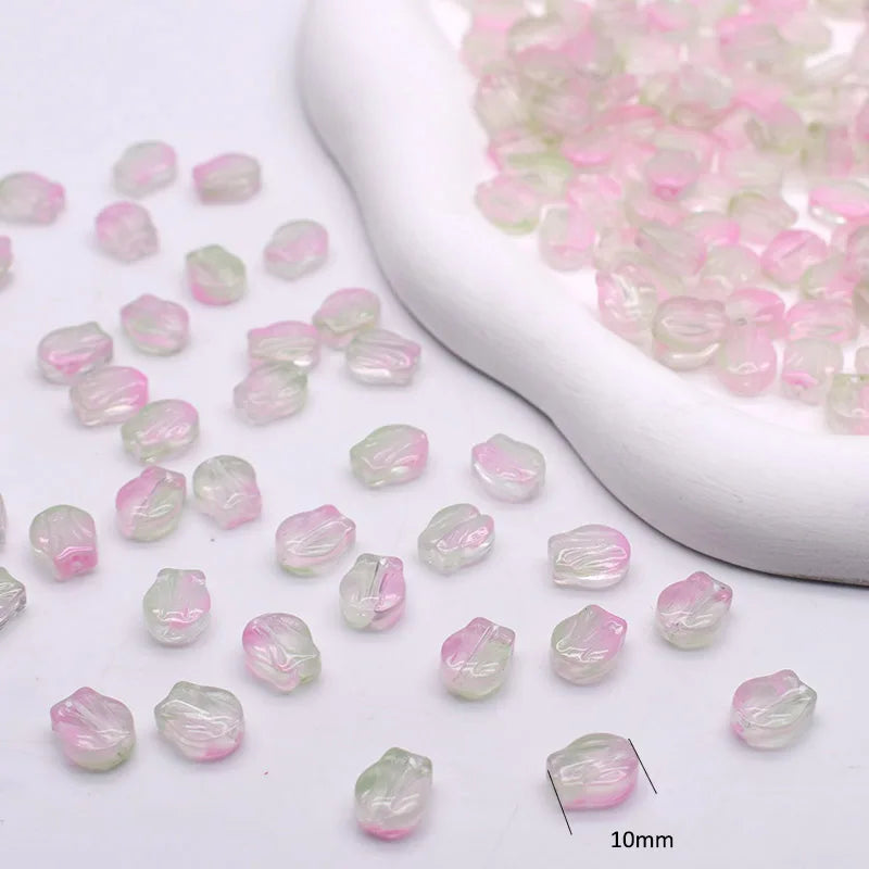 Small pink and green gradient glass beads displayed in a white ceramic mold.