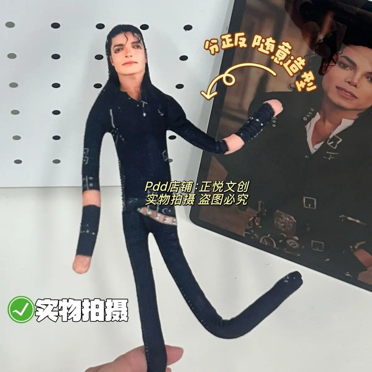 A dark clothing item resembling a full-body suit is displayed, with a hand holding it against a background featuring a portra