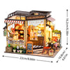 A wooden mini seaside villa dollhouse kit featuring a bakery storefront with furniture and decor.