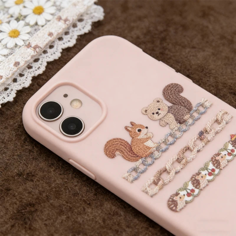 A pink smartphone features decorative fabric-textured sticker strips in shades of brown and beige on a brown surface.