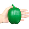 A hand holds a bright green squishy bell pepper fidget toy.