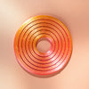 A circular, orange-pink spinner ring with concentric grooves, likely a kinetic desk toy.