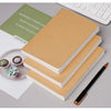 A stack of kraft paper notebooks and a pen on a desk with a quote card.