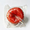 A red watermelon-shaped squishy stress ball fidget toy is sealed in a clear plastic bag.