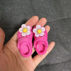 Pair of pink fashion slippers with white and yellow floral accents shown in a hand.