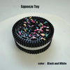 A black and white squeeze toy cake decorated with colorful sprinkles on a white plate.