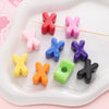 A collection of colorful acrylic letter beads shaped like an 'X' arranged on a white tray.