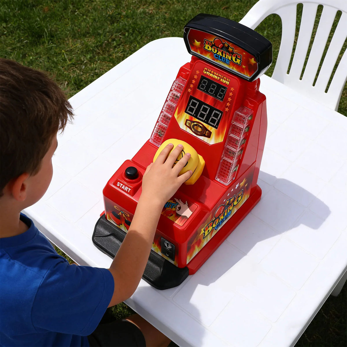 A boy is operating a red interactive finger boxing machine with LED lights and sound effects on a white table.