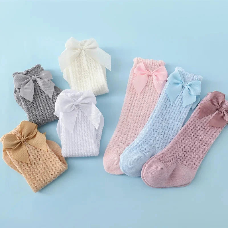A collection of baby girl lace knee socks with bows in various pastel colors including white, pink, blue, and beige.