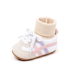 A pair of light beige baby booties with white laces and pink stripes on the side.