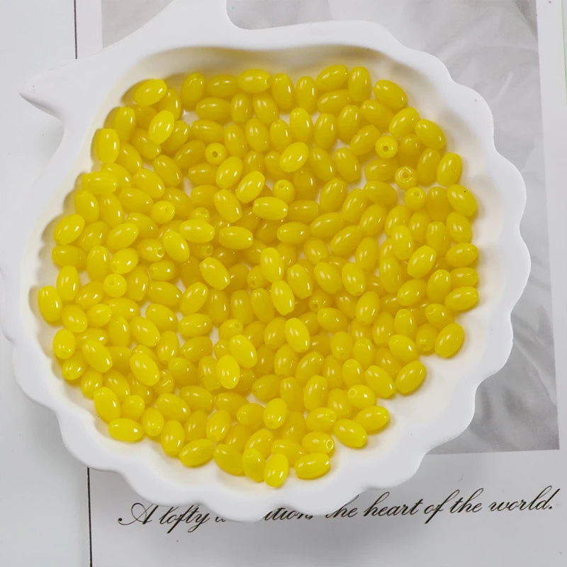 A bowl filled with yellow oval glass rice grain beads for jewelry making