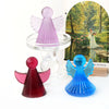 Silicone molds of cherub angels in pink and blue colors displayed next to a painting.