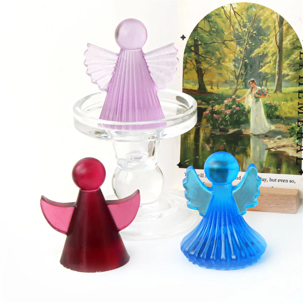 Silicone molds of cherub angels in pink and blue colors displayed next to a painting.