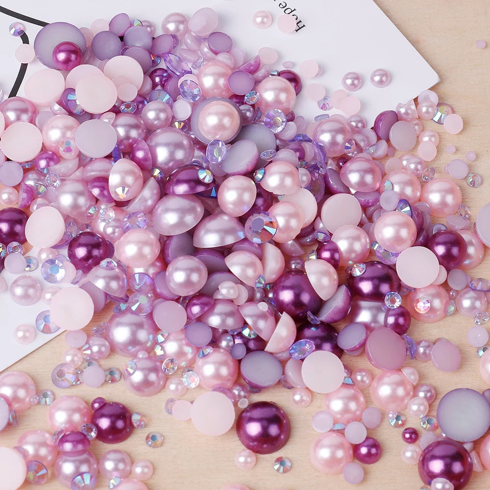 A pile of mixed resin rhinestone pearls in shades of pink, purple, and lavender for crafts and nail art.