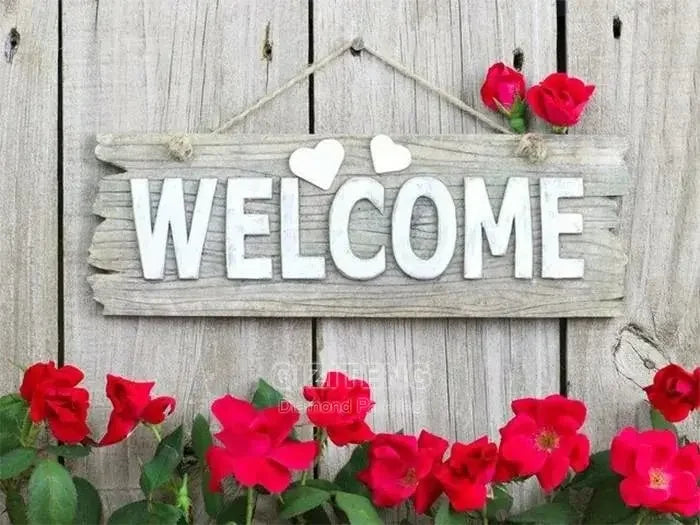 A rustic wooden sign with the word WELCOME and red roses, set against a weathered wooden background.