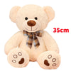 A fluffy, light beige teddy bear plush toy with brown nose and paw pads, tied with a checkered bow.