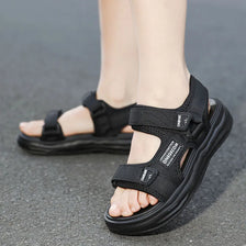 A close-up of black boys' non-slip summer sport sandals worn on a person's foot.