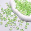 A white scoop filled with small, translucent green glass beads for jewelry making