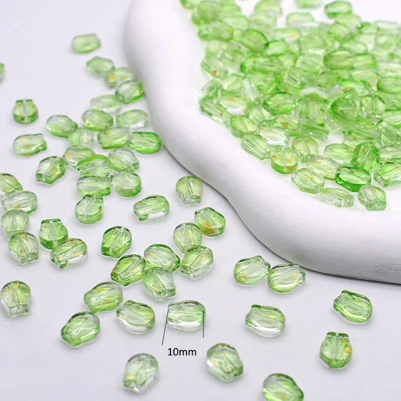 A white scoop filled with small, translucent green glass beads for jewelry making