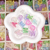 A white mold-shaped tray filled with colorful acrylic alphabet beads for jewelry making and crafts.