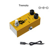 A yellow Tremolo guitar pedal with controls and an output jack, shown next to a cable.