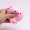 A hand holds a pink squishy stress relief toy shaped like a cute pig.