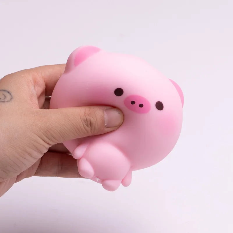 A hand holds a pink squishy stress relief toy shaped like a cute pig.