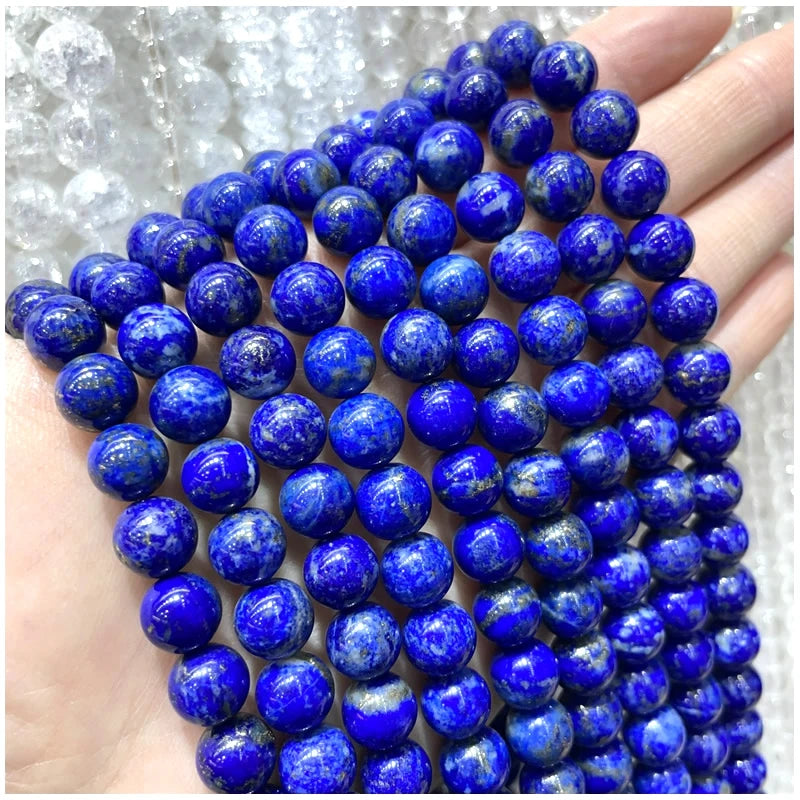 A hand holds a string of deep blue natural stone beads for DIY jewelry making