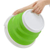 A hand is holding a bright lime green collapsible bucket with a white lid.