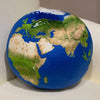 A blue globe depicting the continents of the Earth, showing green landmasses and brown/tan areas.