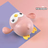 A pink penguin bath toy with yellow feet and a white face is shown on a purple background.