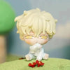 A white blind box figure with light blonde hair and yellow eyes sitting on a green surface.