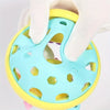 A hand is holding a light blue sensory catch ball rattle toy with yellow accents.