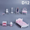 A set of 1:12 scale dollhouse furniture including a pink bed, dresser, mirror, and toilet accessories.