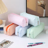 A collection of striped canvas pencil cases in pink, blue, and green are displayed on a white surface.