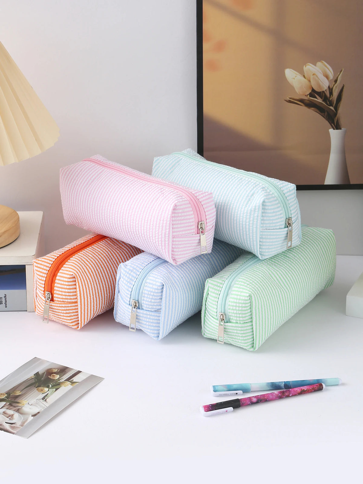 A collection of striped canvas pencil cases in pink, blue, and green are displayed on a white surface.