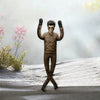 A collectible plush doll of Elvis Presley in a brown leather jacket and sunglasses posing with his arms raised against a snow