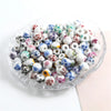 A set of 20 round ceramic flower beads in various colors and patterns, including white, blue, pink, and green, displayed in a