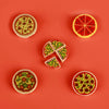 A collection of mini food building blocks featuring pizza, cake, and condiment shaped bricks arranged on an orange background