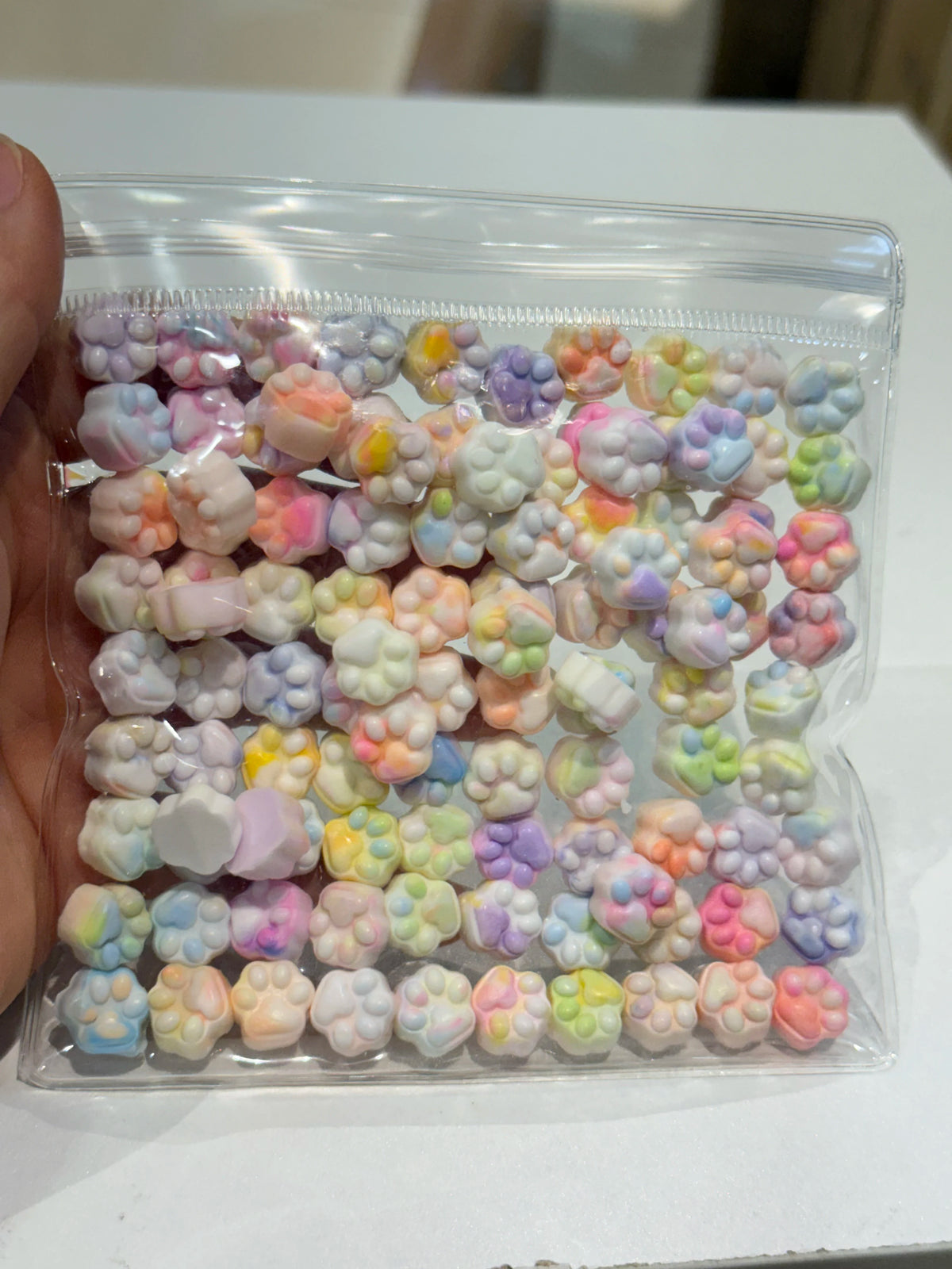 A clear plastic bag filled with numerous pastel-colored, squishy cat paw shaped fidget toys.