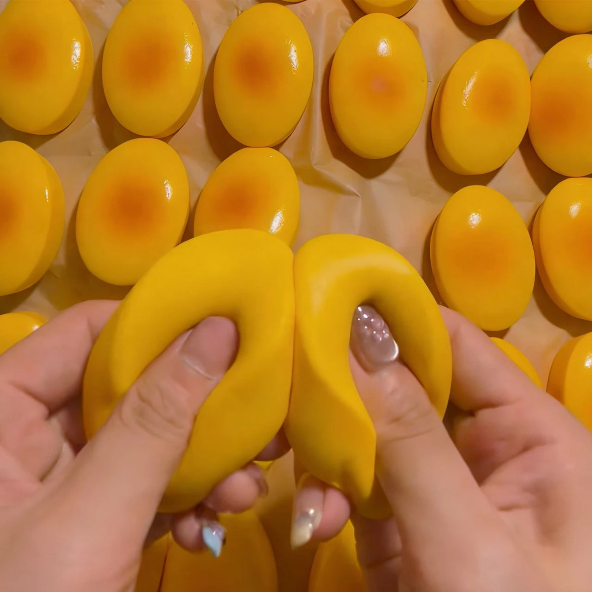 Hands holding a yellow cheese-shaped squishy stress relief toy with orange accents.