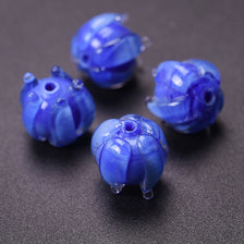 A collection of small, round, blue glass charms or pendants for jewelry making.
